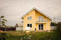 Построенный в с Озерецкое Московской области небольшой каркасный дом 151 кв м с отделкой желтой штукатуркой с балконом и открытой террасой  - мини - 4