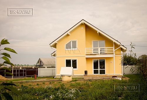 Построенный в с Озерецкое Московской области небольшой каркасный дом 151 кв м с отделкой желтой штукатуркой с балконом и открытой террасой  - 4