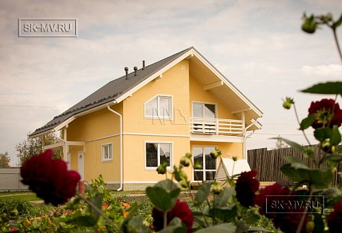Построенный в с Озерецкое Московской области небольшой каркасный дом 151 кв м с отделкой желтой штукатуркой с балконом и открытой террасой  - 1