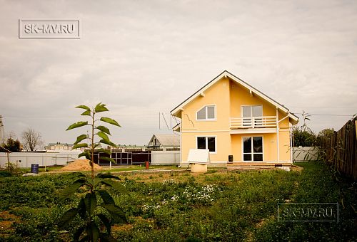 Построенный в с Озерецкое Московской области небольшой каркасный дом 151 кв м с отделкой желтой штукатуркой с балконом и открытой террасой  - 3