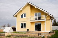 Построенный в с Озерецкое Московской области небольшой каркасный дом 151 кв м с отделкой желтой штукатуркой с балконом и открытой террасой  - мини - 2